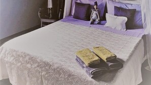 A bedroom with a large bed, a decorative headboard, a nightstand, and a hanging light fixture. - Agriturismo Gocce di Luna (Celle Ligure)