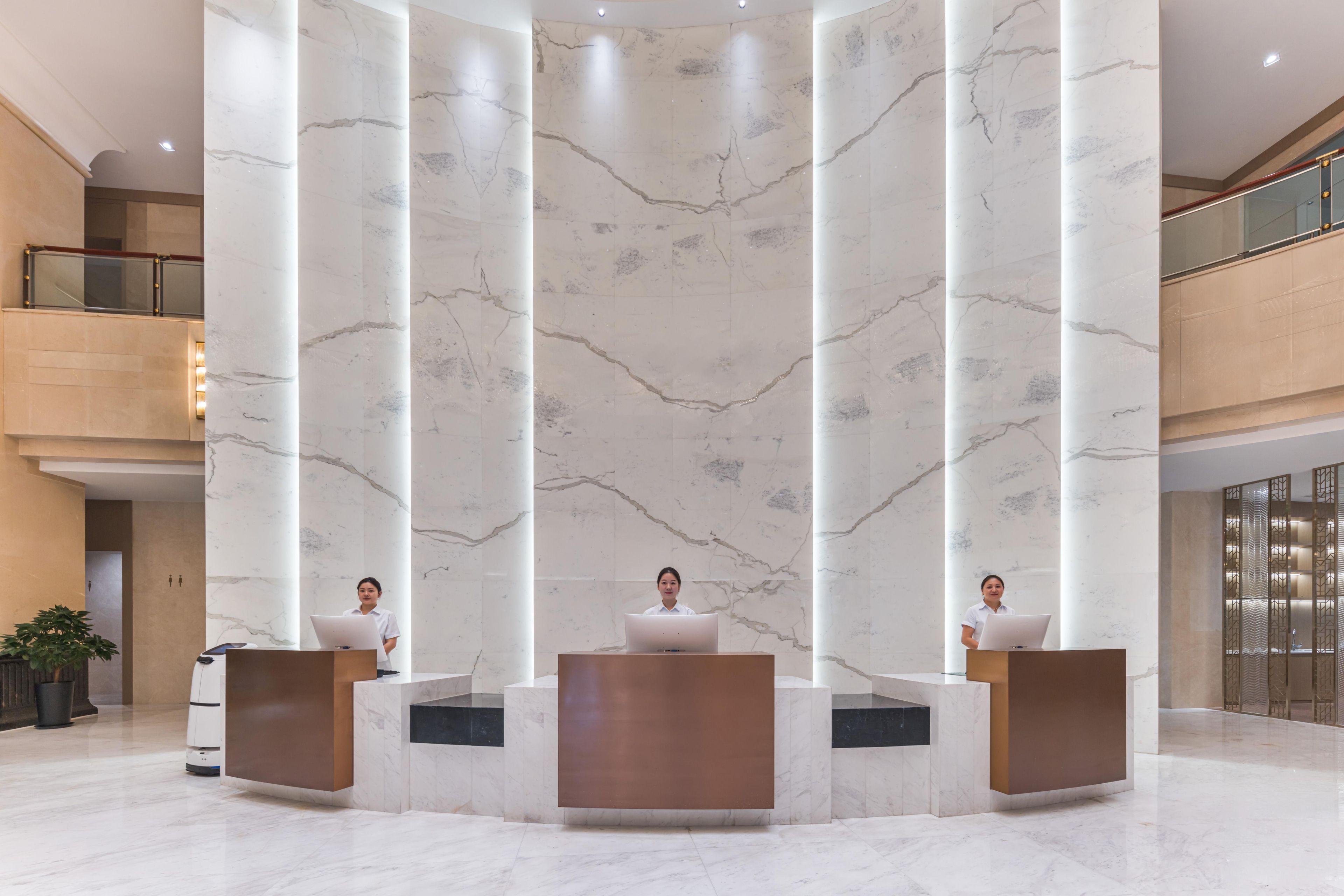 Un'area reception con colonne in marmo, ringhiera in vetro e design moderno.