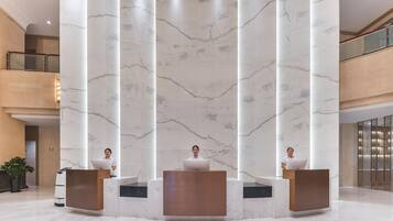 Un'area reception con colonne in marmo, ringhiera in vetro e design moderno.