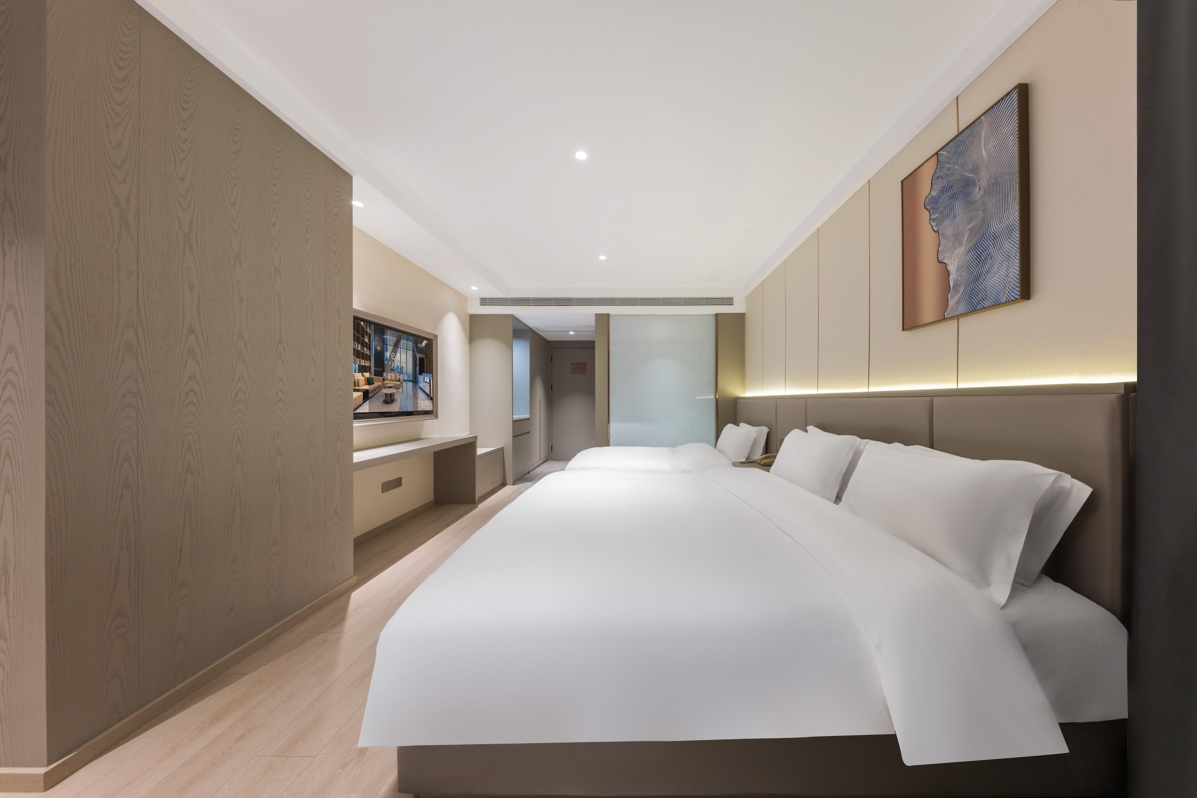 Une chambre d’hôtel moderne avec un grand lit, un bureau et une vue sur le hall d’entrée.