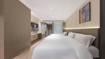 Une chambre d’hôtel moderne avec un grand lit, un bureau et une vue sur le hall d’entrée.