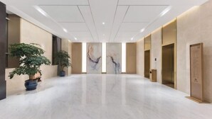 Un hall d’entrée spacieux, doté d’un sol en marbre, de plantes en pot et d’œuvres d’art contemporaines accrochées aux murs.