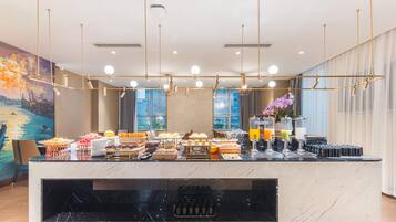 A hotel reception area with a marble counter, various food items, and a painting on the wall.