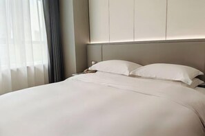 Un lit bien fait, avec du linge de lit blanc, dans une chambre d’hôtel.