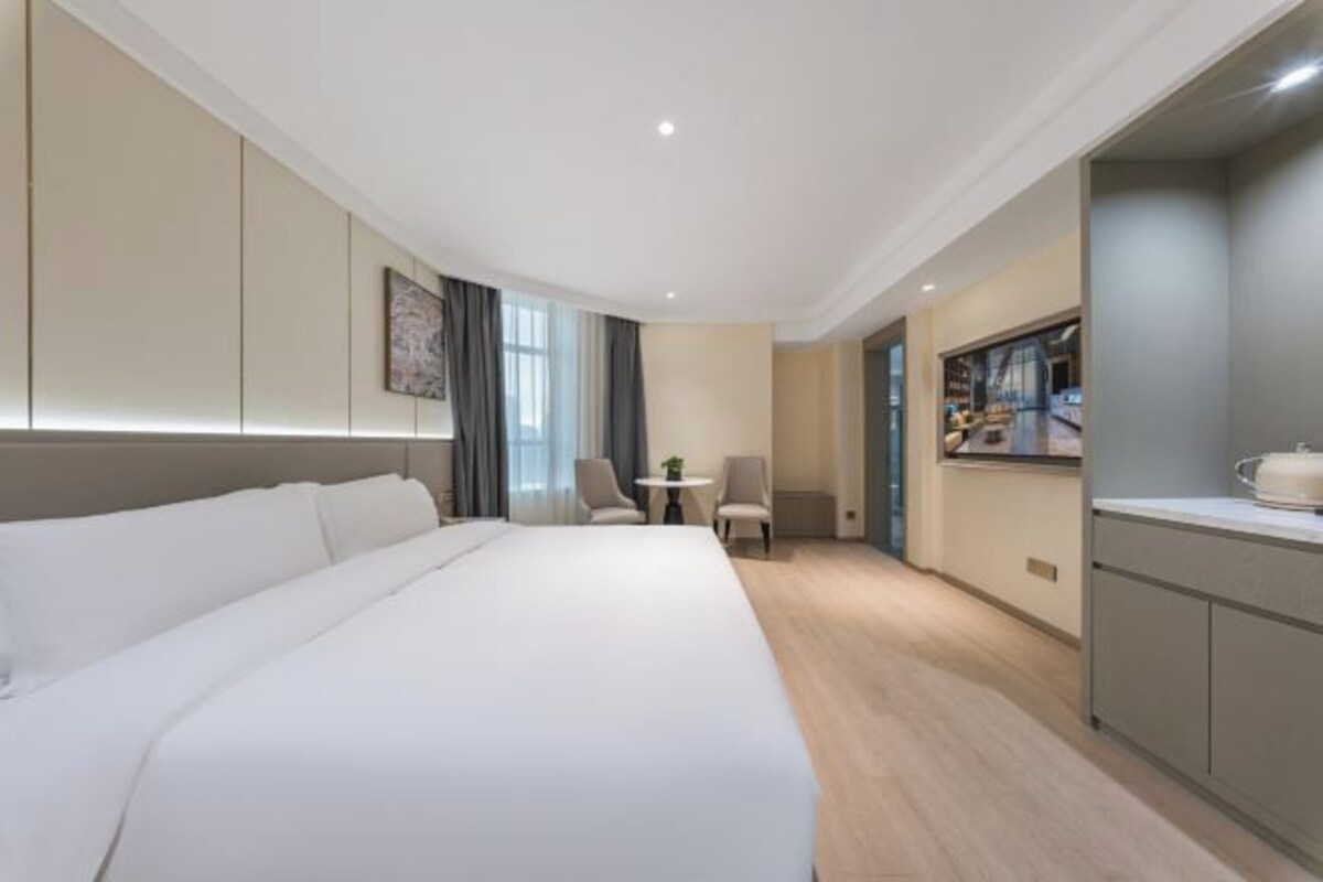 Een hotelkamer met een groot bed, een kleine tafel, een stoel, een kitchenette en een televisie.