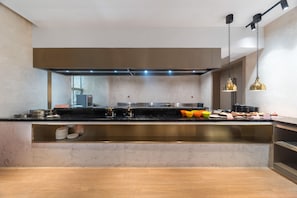 A modern kitchen with a central island, stainless steel appliances, and a black countertop.