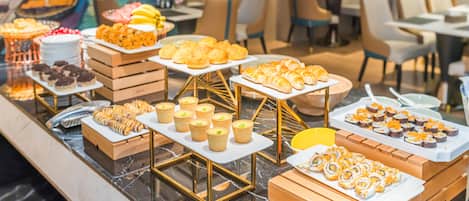 A buffet with various food items including pastries, sushi, and other dishes.