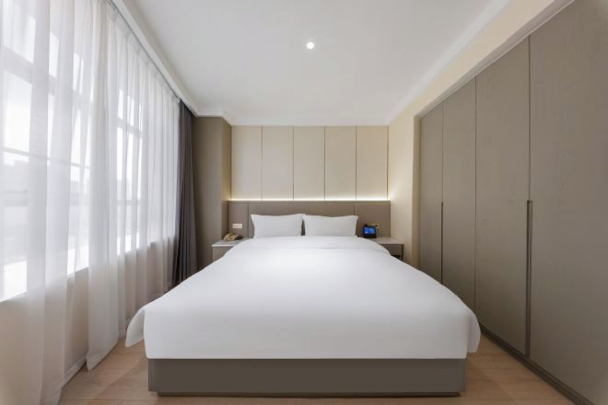 Een moderne hotelkamer met een groot bed, een nachtkastje met lamp en een kledingkast.