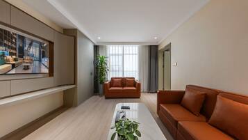 Una sala de estar moderna con un televisor de pantalla plana grande, dos sofás, una mesa de centro y una planta en maceta.