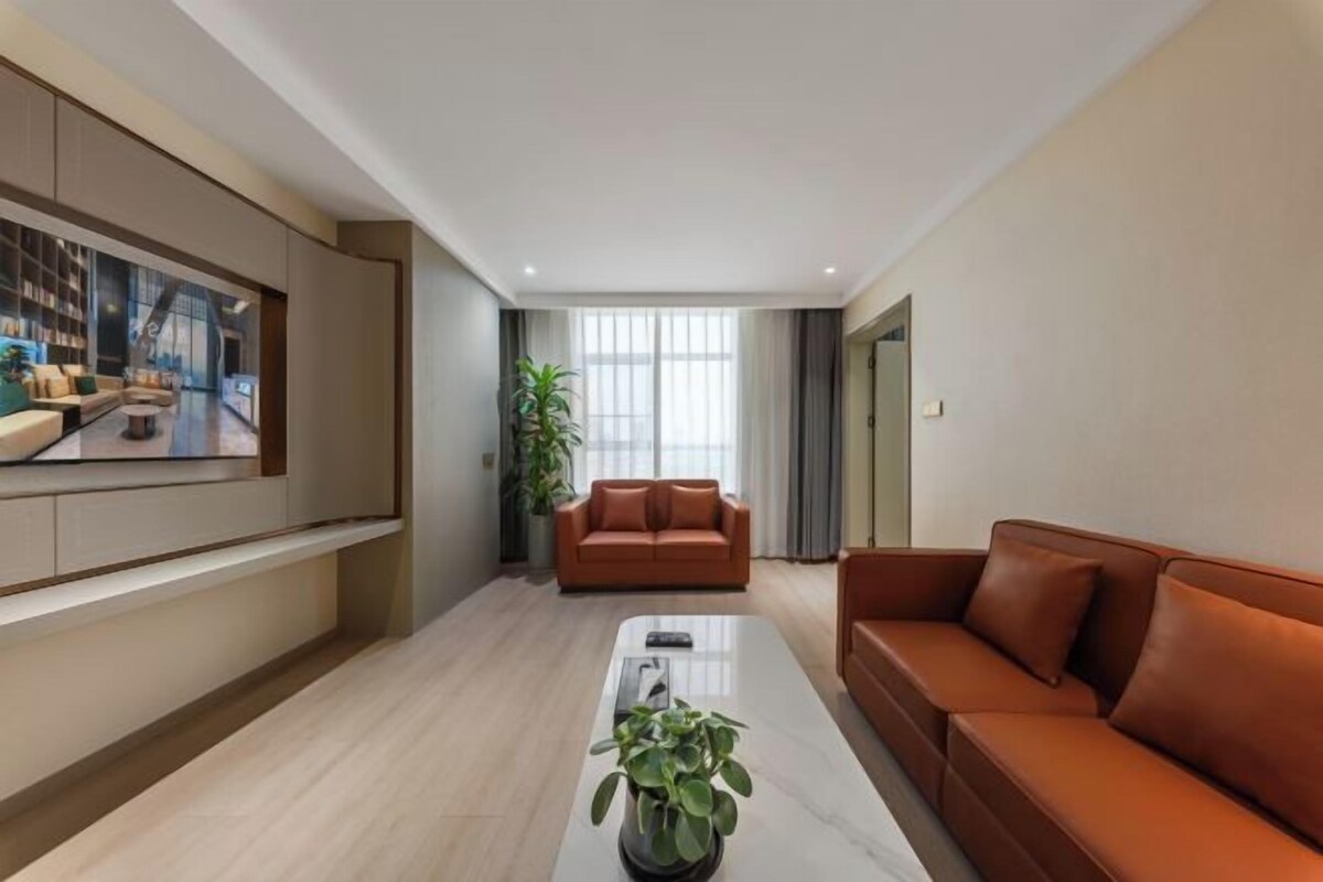 Ein modernes Wohnzimmer mit einem großen Flachbildfernseher, zwei Sofas, einem Couchtisch und einem Blumentopf.