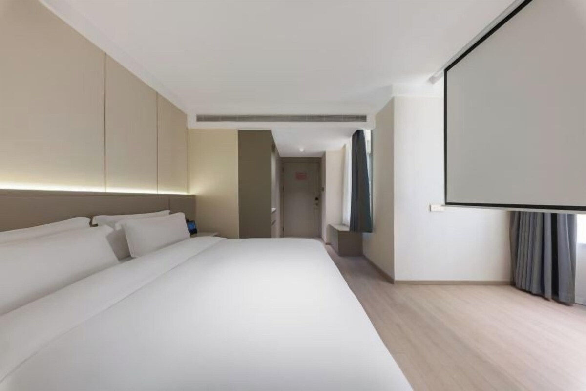Une chambre d’hôtel moderne dotée d’un grand lit, d’un téléviseur à écran plat et d’un design minimaliste.