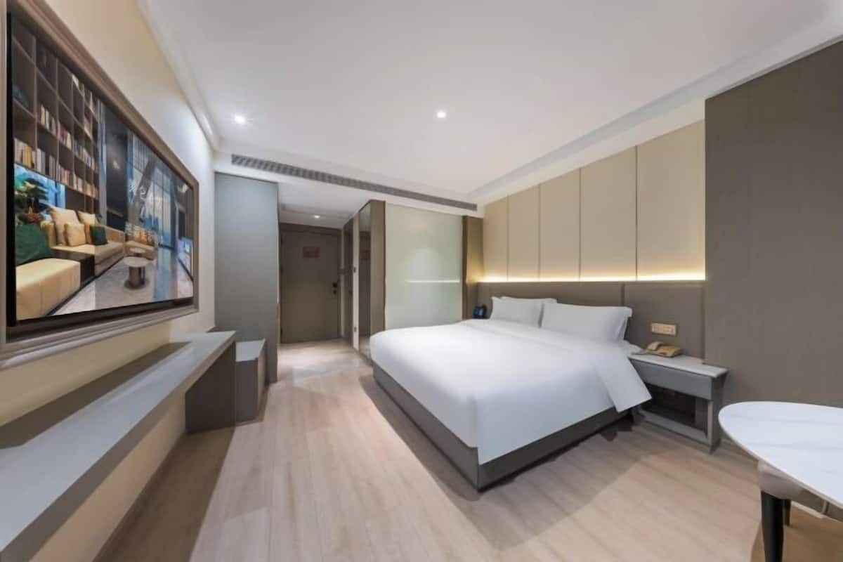 Ein modernes Hotelzimmer mit einem großen Bett, Nachttischen, einem Fernseher und einem kleinen Tisch.