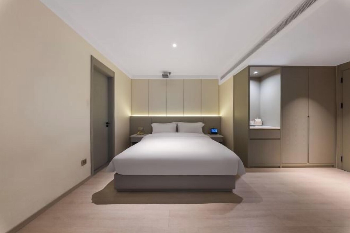 Une chambre à coucher moderne avec un grand lit, des tables de chevet et une armoire.