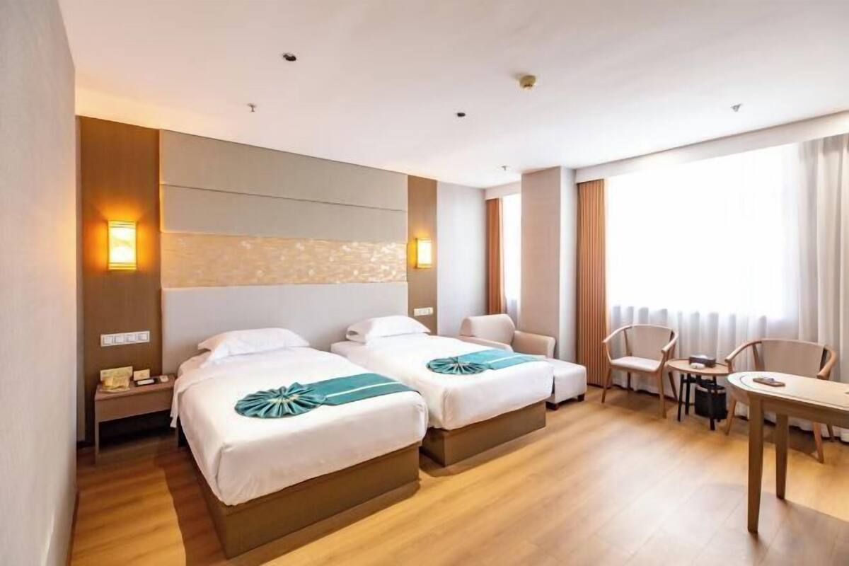 A hotel room with two beds, a desk, and a chair.
