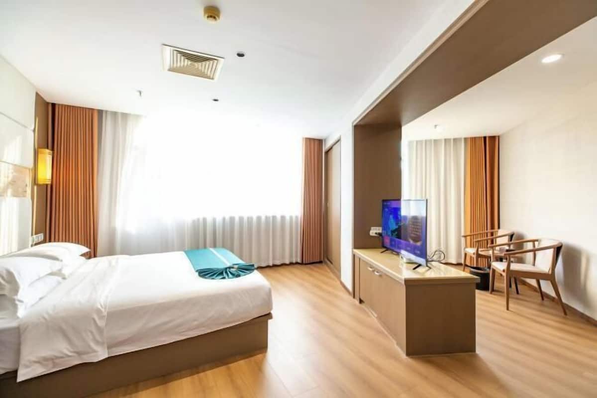 Una habitación de hotel con una cama, un escritorio con televisor y un rincón de descanso.