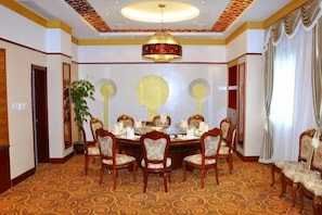 Een elegante eetzaal met een ronde tafel, stoelen en een kroonluchter.