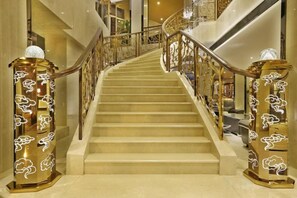 Una imponente escalera con barandillas ornamentales y pilares decorativos, que conduce a un piso superior.