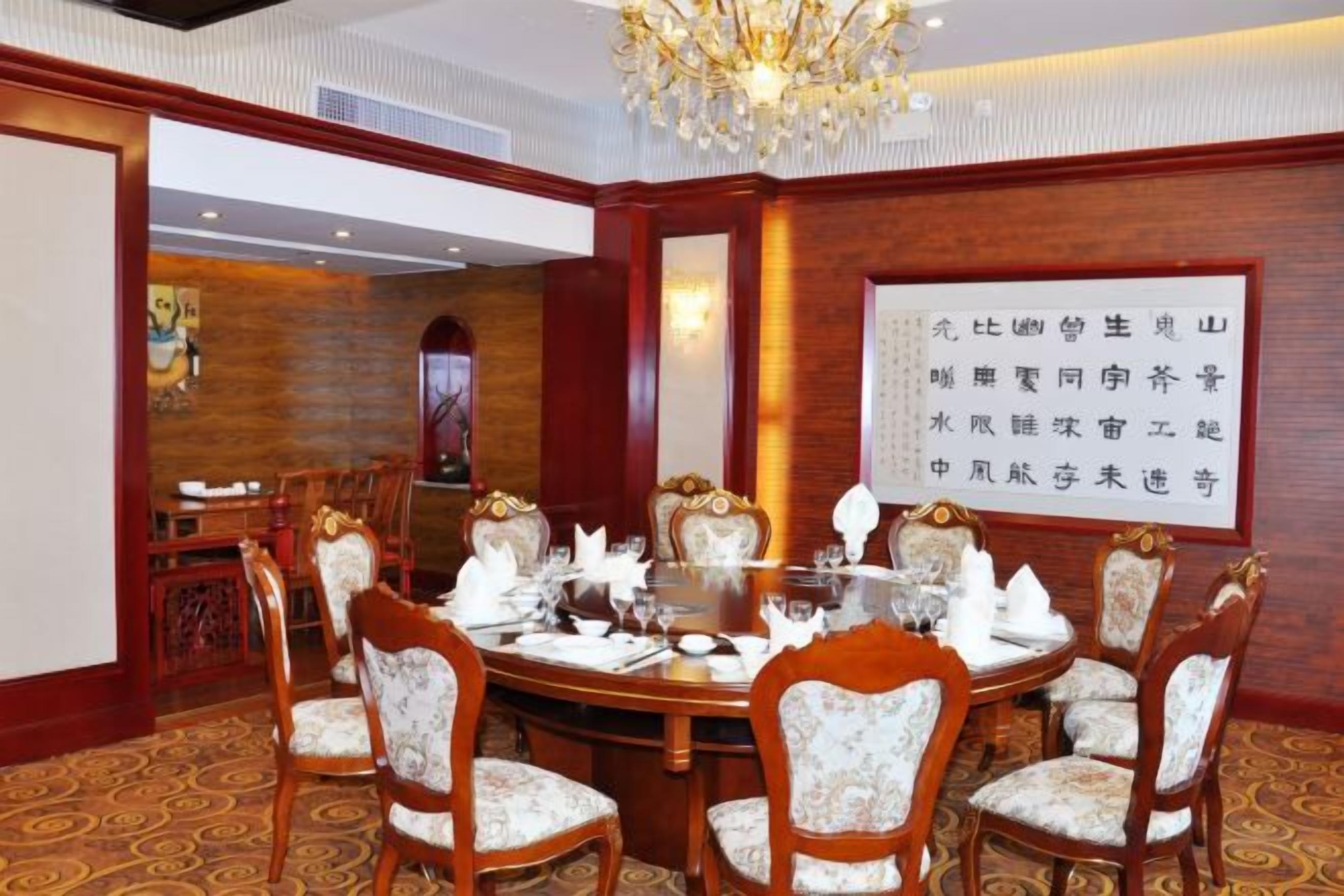 Un comedor formal con una mesa redonda, sillas y una araña.