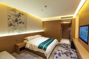 Ein modernes Hotelzimmer mit einem Bett, Nachttisch, Wandkunst und einem Fernseher.