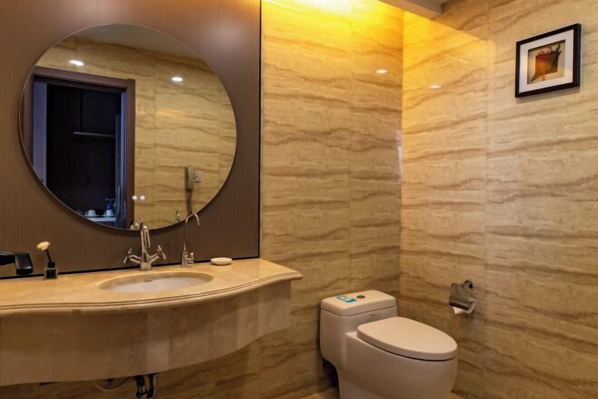 Une salle de bain moderne avec un miroir rond, un lavabo, des toilettes et un sèche-mains fixé au mur.