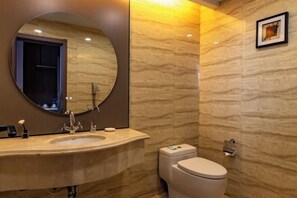 Une salle de bain moderne avec un miroir rond, un lavabo, des toilettes et un sèche-mains fixé au mur.