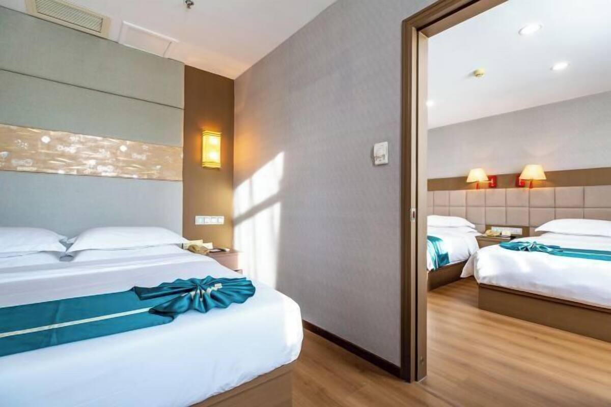 Habitación de hotel con dos camas, un espejo grande y una lámpara de pared.