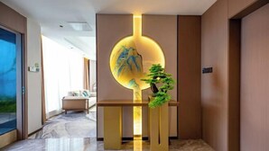 Un hall d’entrée moderne avec un comptoir d’accueil, une œuvre d’art circulaire fixée au mur et une plante en pot.