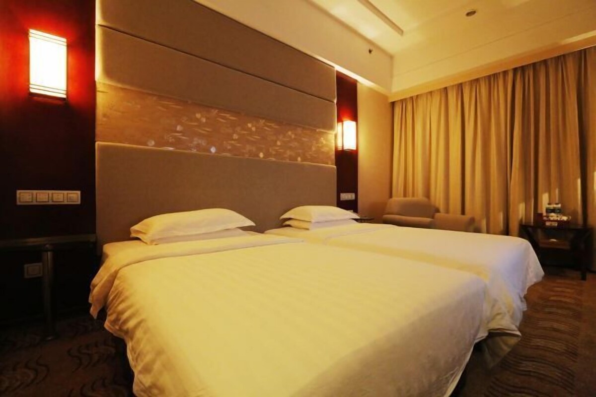Une chambre d’hôtel avec deux lits, une grande tête de lit, une chaise et une table de chevet avec une lampe.