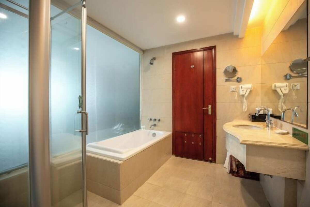 Une salle de bain moderne dotée d’une douche à parois de verre, d’une baignoire sur pied et d’un meuble-lavabo avec un miroir et un porte-serviettes.