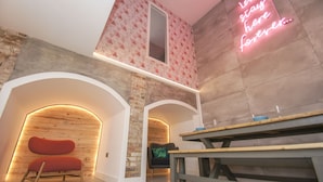 A modern interior with exposed brick walls, wooden arches, and a neon sign.