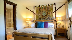 A bedroom with a wooden bed, two bedside tables with lamps, a decorative headboard, and a mirror.