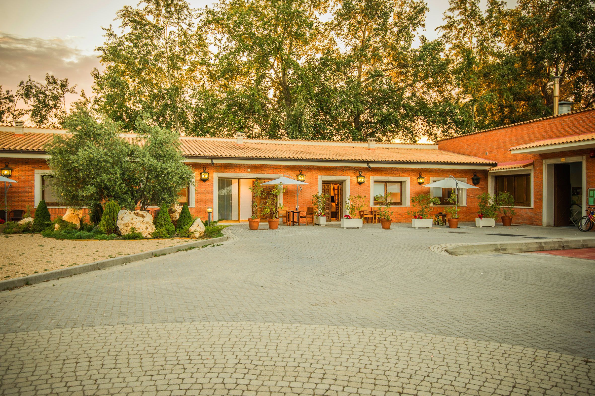 A courtyard with a brick building, potted plants, and outdoor seating.