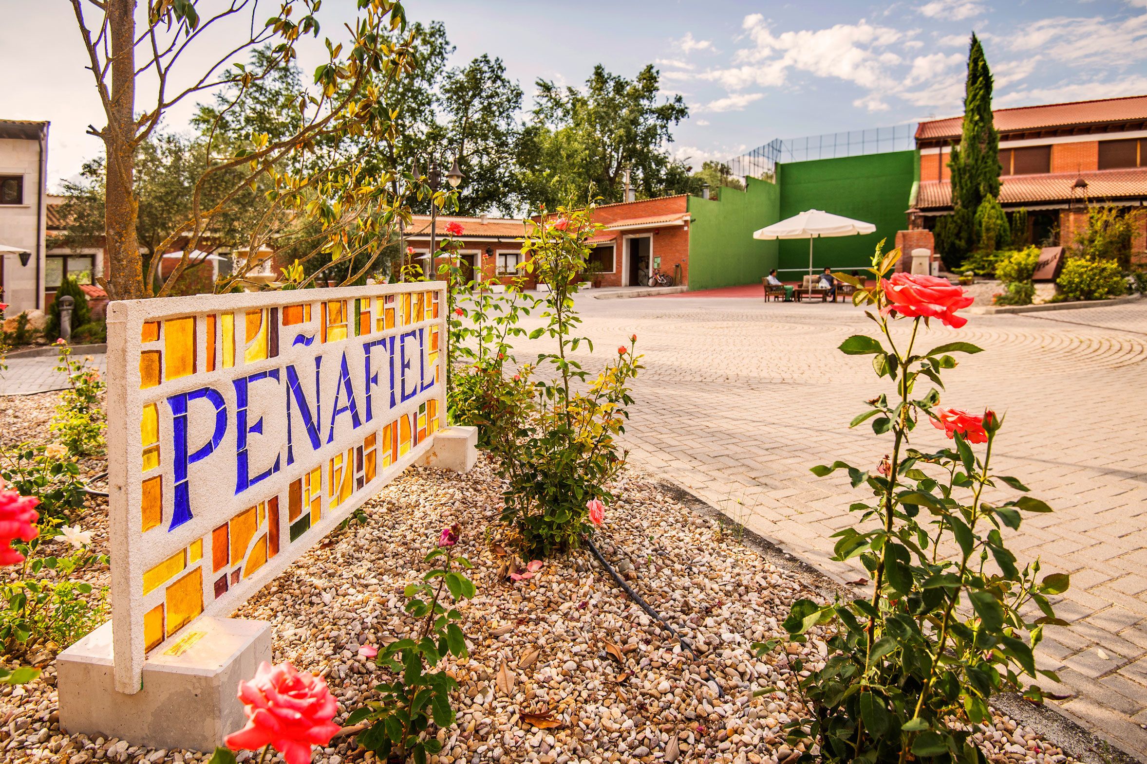 A sign for PENAFIEL hotel with a tiled courtyard and surrounding greenery.