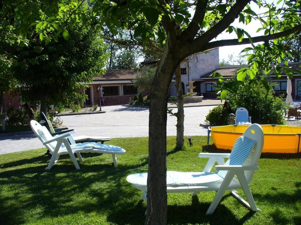 Un patio con dos sillones, una piscina amarilla y un edificio al fondo.