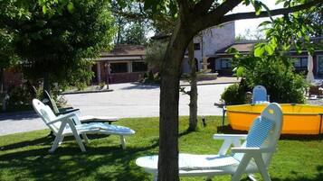 Un patio con dos sillones, una piscina amarilla y un edificio al fondo.