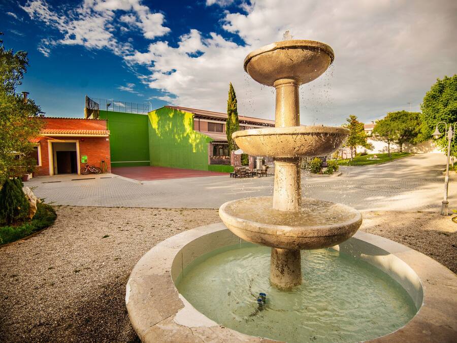Ein mehrstufiger Brunnen in einem Innenhof mit einem Gebäude im Hintergrund.