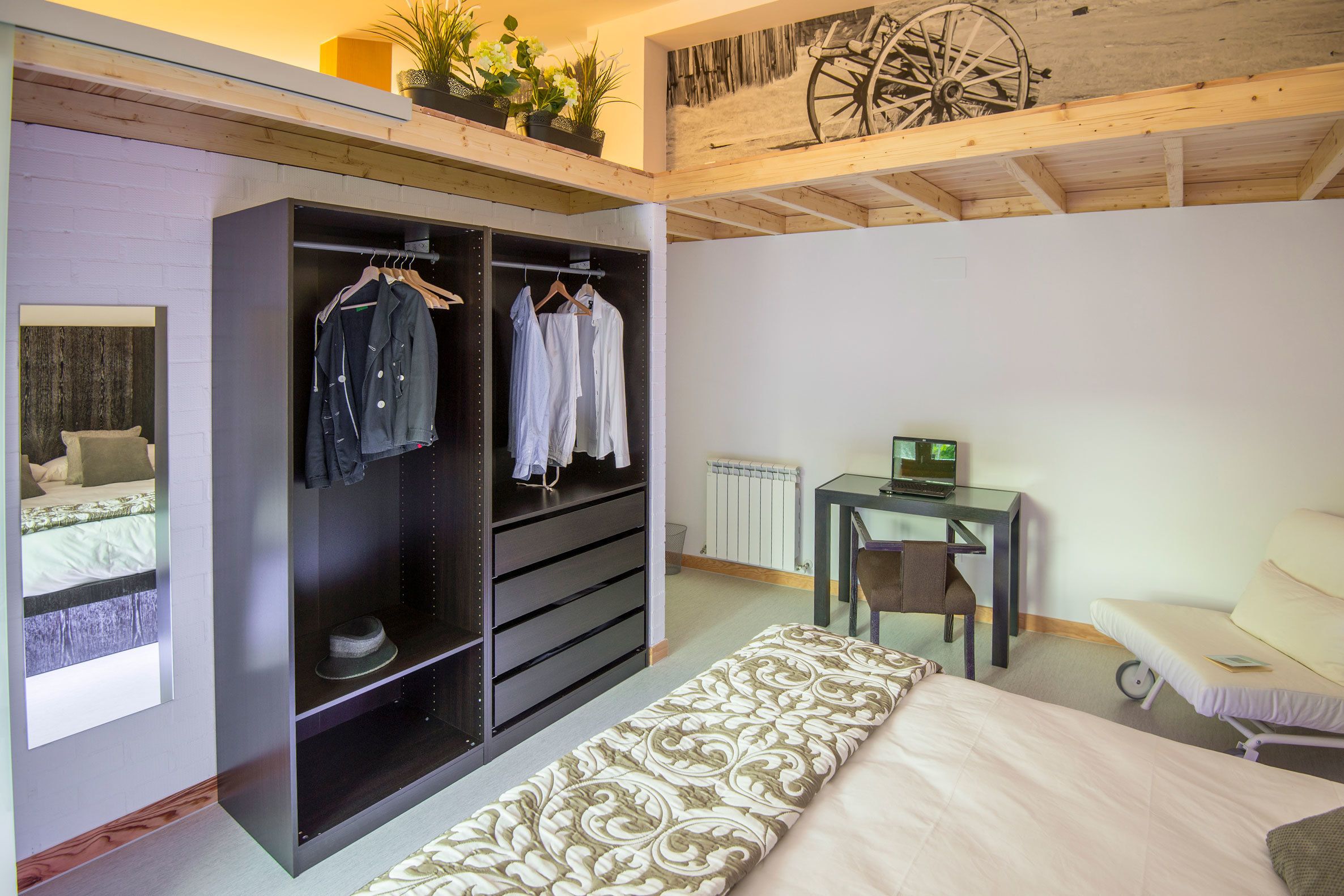 A bedroom with a bed, a bedside table, a desk, a chair, a wardrobe, and a radiator.