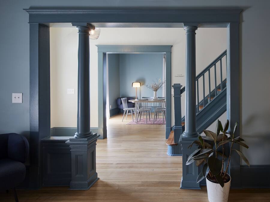 Ein Flur mit Holzboden, einer Treppe und einem Essbereich im Hintergrund.
