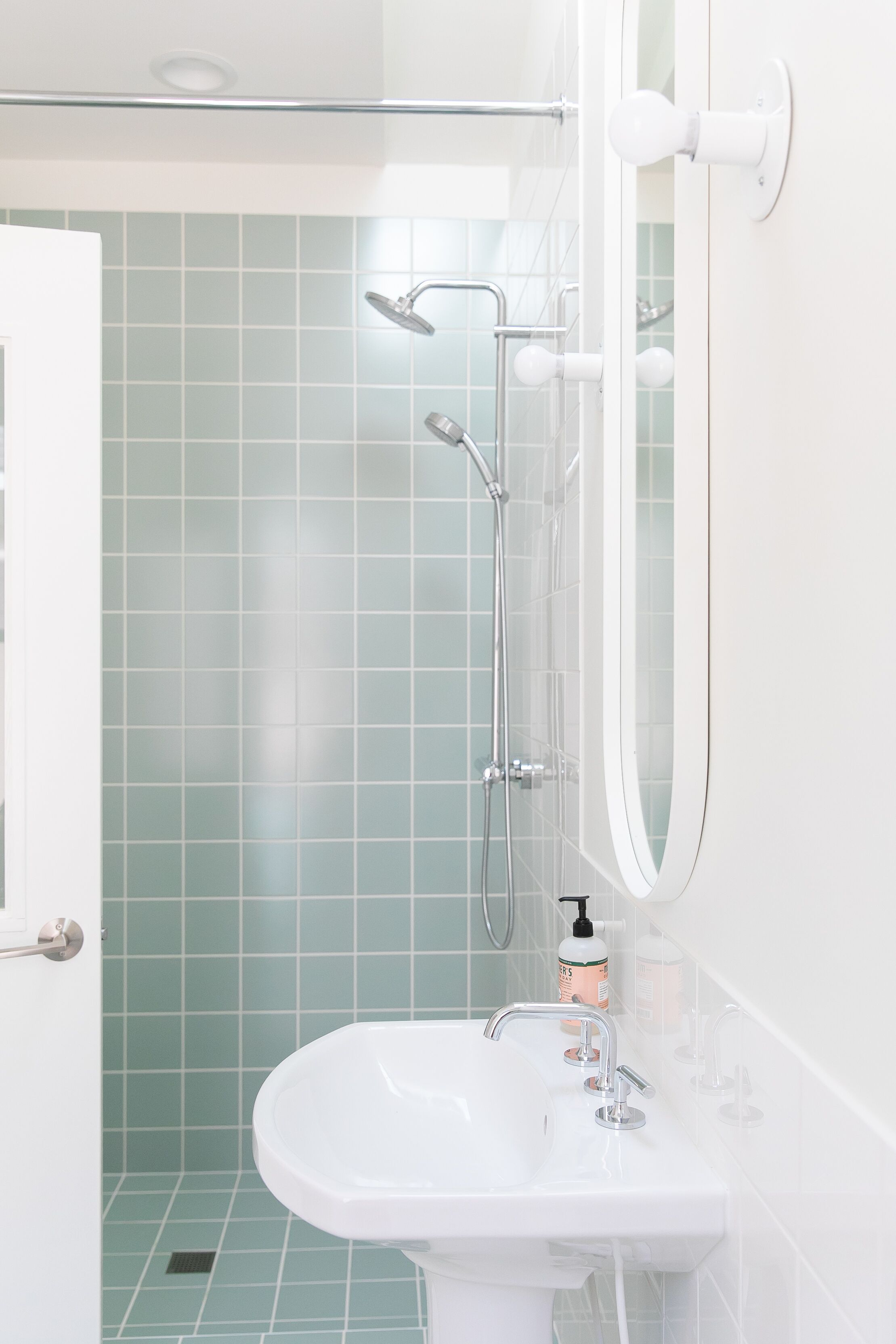 A bathroom with a white sink, a mirror, and a shower with a glass door.