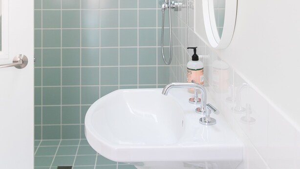 A bathroom with a white sink, a mirror, and a shower with a glass door. - Guest House Raleigh (Raleigh)