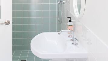 A bathroom with a white sink, a mirror, and a shower with a glass door.