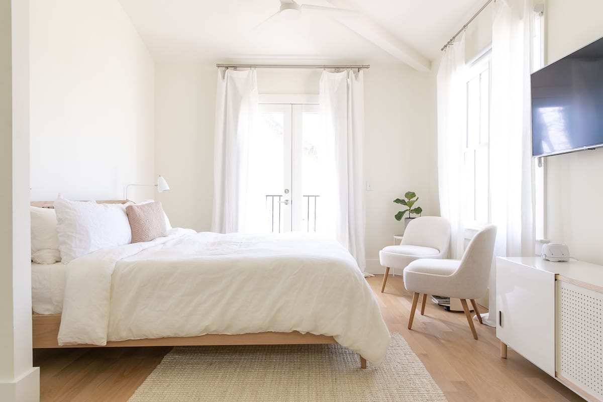A modern bedroom with a bed, a desk, and a TV.