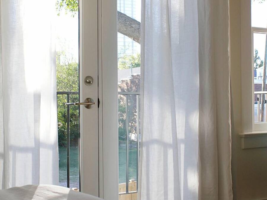 Una camera da letto con un letto, una porta che dà su un balcone e una finestra.