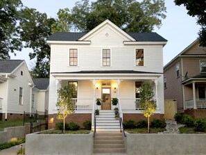 A two-story house with a front porch, a central staircase, and a brick foundation. - Guest House Raleigh (Raleigh)