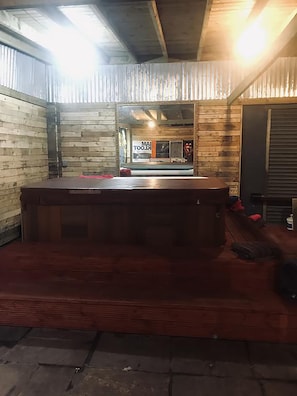 A room with a wooden floor, a wooden bench, and a window with a view of the outside.