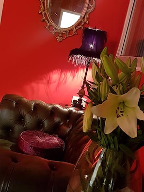 A red wall with a mirror and a lamp.