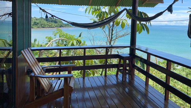 Terraza de madera con hamaca, con vistas a la costa.