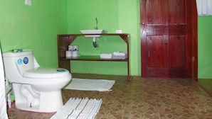 Un baño con inodoro, lavamanos y puerta de madera.