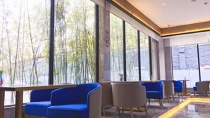 Ein modernes Interieur mit großen Fenstern, blau-grauen Sitzgelegenheiten und einem polierten Boden.