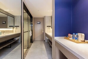 A modern bathroom with a glass shower enclosure, a vanity with a mirror, and a tray with toiletries. - Wangfu Hotel (Fuzhou Donghua University of Technology) (Fuzhou)
